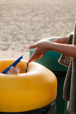 Genç bir kadın B 'deki bir plaj temizliği sırasında plastik atık topluyor.
