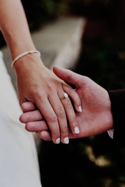 Erkek ve kadın el ele tutuşup nişan yüzüğünü gösteriyorlar.