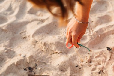 Genç bir kadın B 'deki bir plaj temizliği sırasında plastik atık topluyor.