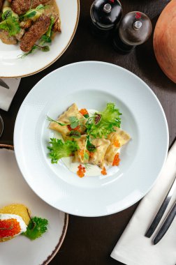 Bir restoranda soslu ravioli, otlar ve havyar.