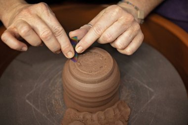 Potter dönen çarkın üzerindeki kil parçasına karmaşık detaylar kazıyor.