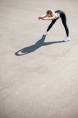 Sportif kadın koşmak için bacaklarını açıyor ve ısıtıyor.