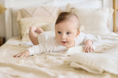 Mavi gözlü gülümseyen bebek, rahat bir yatakta yatıyor.