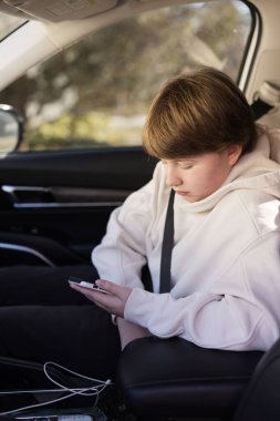 iPhone 'una odaklanmış bir SUV içindeki genç çocuk.