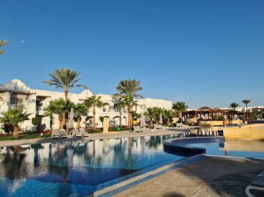 Havuzun kıyısında evler ve palmiyeler.