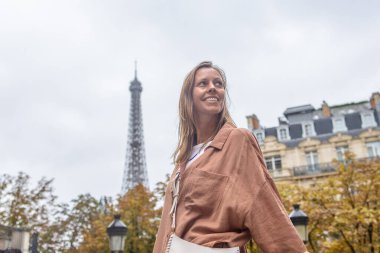 Arkadaki Eyfel Kulesi 'nin tepesinde soluna bakan kadın.