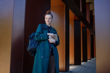 Modern üniversite binasının yanındaki gözlüklü kız.