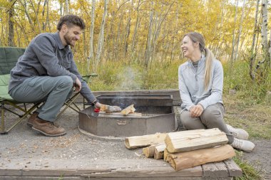 Çiftler kamp yaparken ateş yakar.
