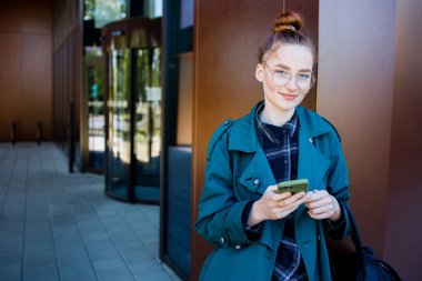 Akıllı telefonlu kızıl öğrenci portresi.