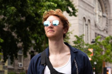 Güneş gözlüklü genç bir adam, güneşli bir öğleden sonranın tadını çıkarıyor.