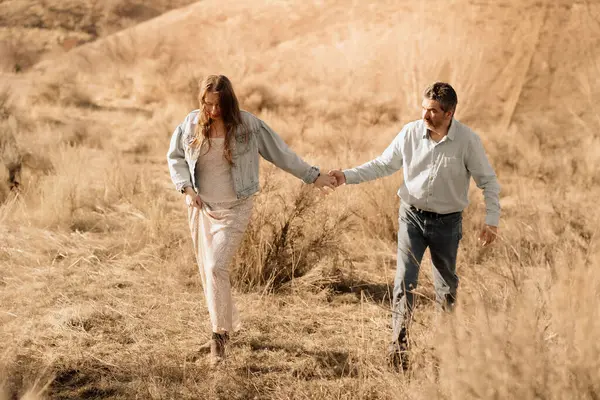 Bir çift el ele yürür, baharda çimen tarlalarını keşfederler.