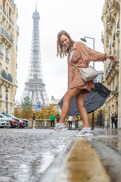Arka planda Eyfel Kulesi ile sokaklarda dans eden bir kadın.