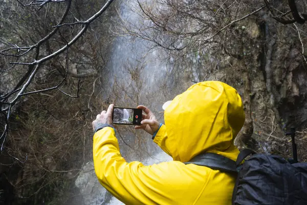Yürüyüşçü yağmur ormanlarında akıllı telefonuyla bir şelaleyi filme alır.