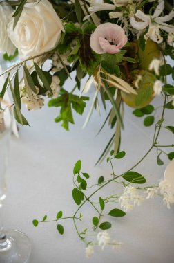 Beyaz güller, şakayıklar ve yeşillikler ile narin bir çiçek aranjmanı.