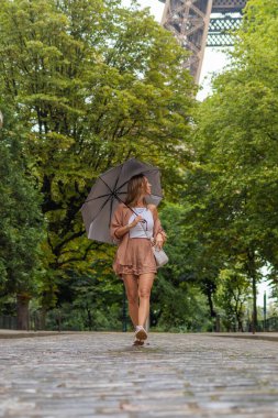 Eiffel Kulesi 'nin yakınındaki kaldırım taşlı bir sokakta yürüyen kadın.