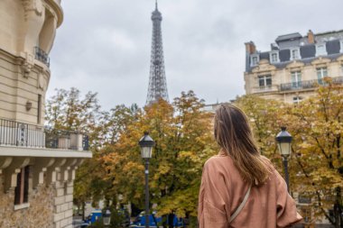 Eiffel Kulesi 'nde bulutlu bir günde bakan bir kadının arka görüntüsü.