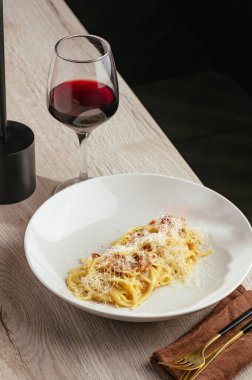 Parmesan peynirli spagetti ve bir bardak şarap.