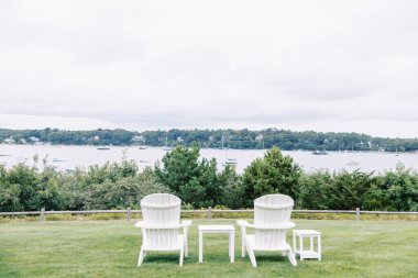 Cape Cod Limanı 'ndaki teknelere bakan yatay iki Adirondack sandalyesi