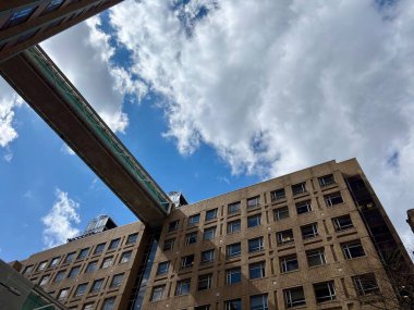 Dramatik bulutlar ve mavi gökyüzü ile tuğla bina üzerinde Skybridge