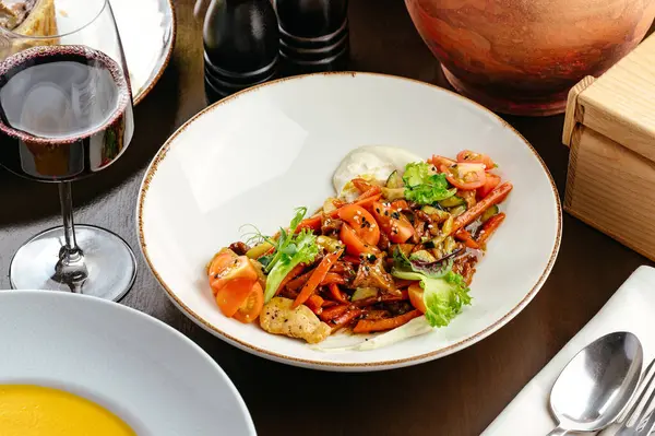 Tavuklu sıcak sebze salatası ve bir bardak şarap.