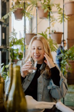 40 'larında elinde içkiyle gülümseyen bir kadın.