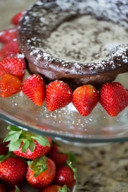 Şekerle tozlanmış çikolatalı pasta, taze çilekle süslenmiş..