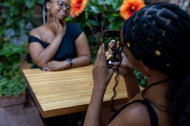 Cep telefonlu siyah kadın kahve randevusu.