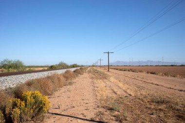 Tren rayları ve telgrafı olan kırsal çöl manzarası.