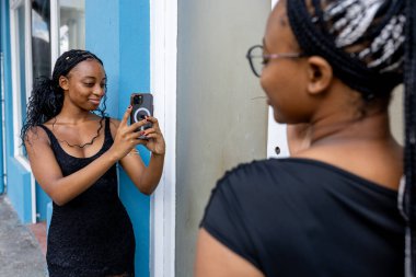 Genç zenci kadın şehir telefon teknolojisi kullanıyor.