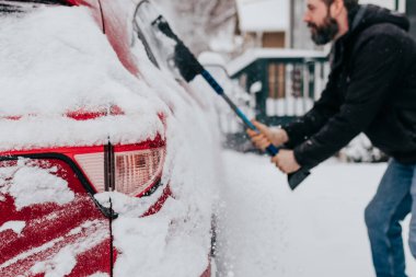 Adam kar fırtınasından sonra sabahın erken saatlerinde arabadan karı temizler.
