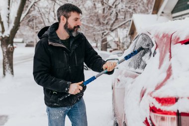 Adam kar fırtınasından sonra sabahın erken saatlerinde arabadan karı temizler.