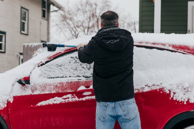 Adam kar fırtınasından sonra sabahın erken saatlerinde arabadan karı temizler.