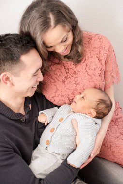 Aileler bebeğe gülümserken onları sevgiyle kucaklarlar.