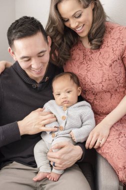 Mutlu ebeveynler evde kucağında bebekle otururlar.