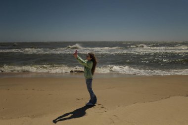 Plaj tatilinde telefonla selfie çeken güzel bir genç.