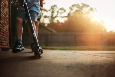 Altın ışıkta scooter 'da oynayan çocuklar