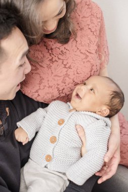 Aileler, kucakladıklarında bebeğe sevgiyle gülümserler.