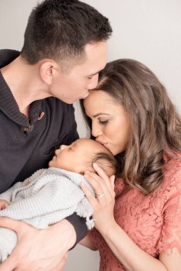 Sevgi dolu ebeveynler yeni doğan bebeklerini kafasından öperler.