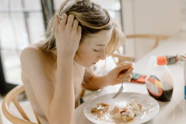 Çocuk güneş ışığında şuruplu Fransız tostunun tadını çıkarıyor.