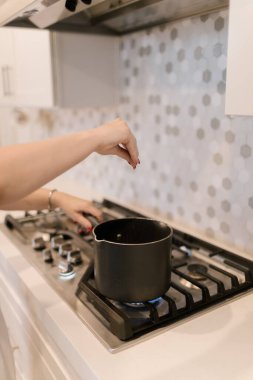 Aşçıbaşı ocakta kaynayan tencereye tuz serpiyor..