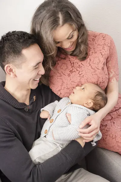 Anne babalar neşe ve sevgiyle bakarken bebek gülümser.