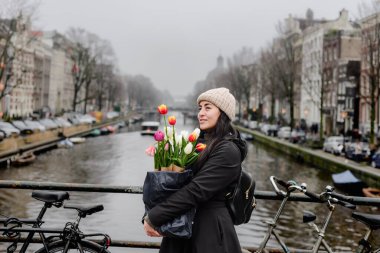 Amsterdam 'da Kanal Köprüsü' nde Bisikletli Kadın Tutan Lale