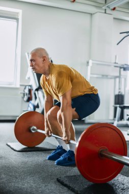Spor salonunda halterle kaldırma egzersizi yapan adam.