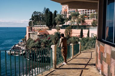 Adam otelden deniz manzarası seyrediyor.