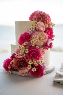 Deniz kenarındaki kayalıklarda Parlak Çiçek Şelaleli Romantik Düğün Pastası