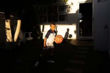 Genç melez Afrikalı çocuk, maçtan sonra evde basketbol oynuyor.