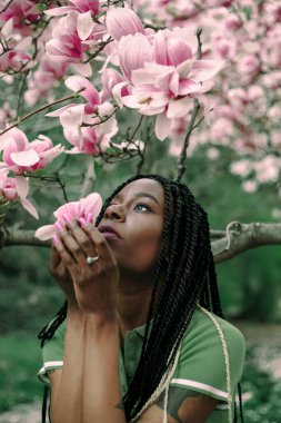 Çiçek açan manolya ağacının altında güzel siyah bir kadın.