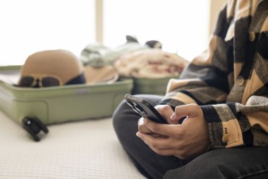 Arka planda paketlenmiş bavulla el ele tutuşup yatağın üzerinde