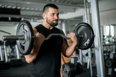 Spor salonunda halter kaldırmaya kararlı bir adam.