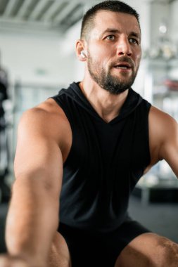 Odaklanmış kaslı adam spor salonunda çalışıyor, terliyor ve kararlı.